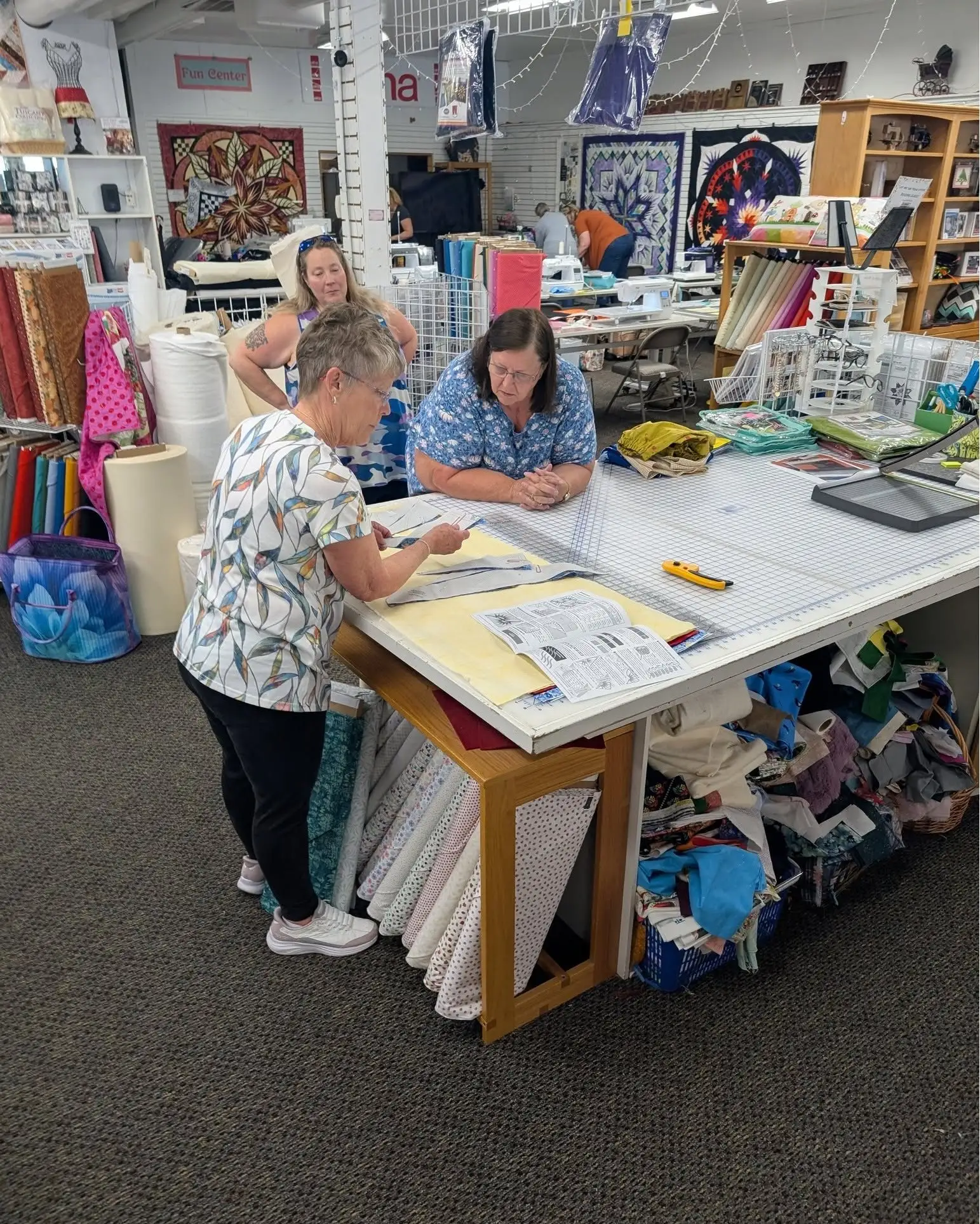 Two quilters reviewing a Quiltworx pattern at a cutting table