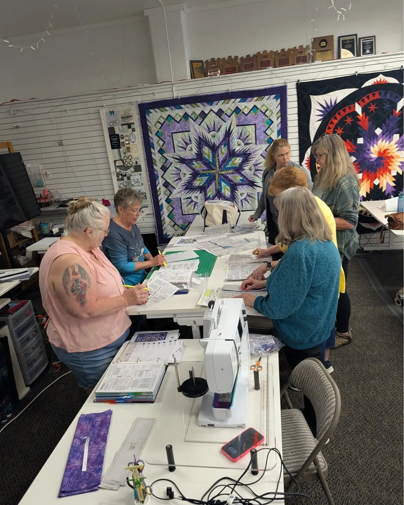 A group of quilters working together around a table during class